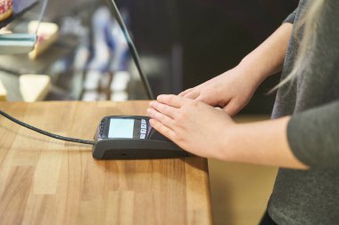 Bir kız bir kafedeki banka terminalinde şifre giriyor. Kredi kartı ödemesi. Mali güvenlik. 