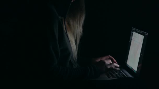 Hacker di atas kepala di kap mesin yang bekerja dengan laptop mengetik teks di kamar gelap . — Stok Video