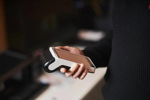 Bank terminal for contactless payment. Young man holds a terminal in his hands