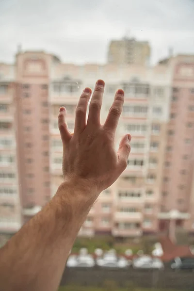 Young man on self-isolation. Stay home. Hand on the window.