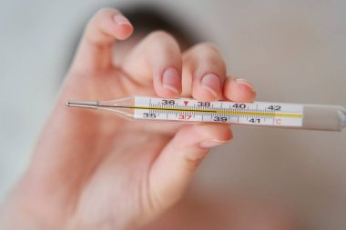 Kızın elinde termometre var. Bir termometrede yüksek vücut sıcaklığı. 