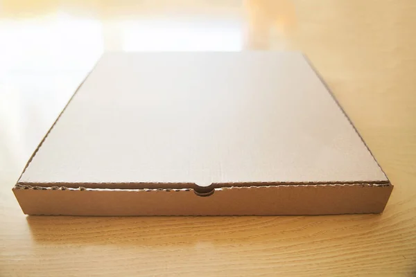 Cartón marrón en blanco Caja de papel de pizza aislada en la mesa . — Foto de Stock