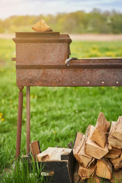 Ateşte et pişirmek için barbekü. Ateş yakmak için hazırlanmış odunlarla. — Stok fotoğraf