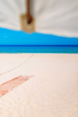 Boş beyaz kumsal ve güneş şemsiyesi, mavi gökyüzü