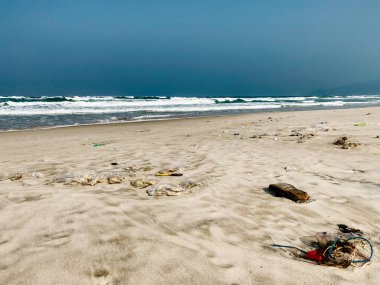 Plastik şişeler ve kumlu deniz kıyısına atılan diğer çöpler., 