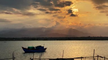 4k video, dağları manzaralı bir nehirde güzel bir gün batımı, geleneksel bir Asya balıkçı teknesi demirli..