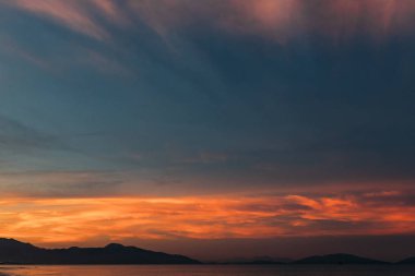 Güzel bir gün doğumu, bulutların arasından güneşin batışı, bulutların arasından güneş ışınları, küçük dalgalarla kumlu deniz kıyıları, denize yakın tropikal bir bölgede sıcak bir sabah ışığı..