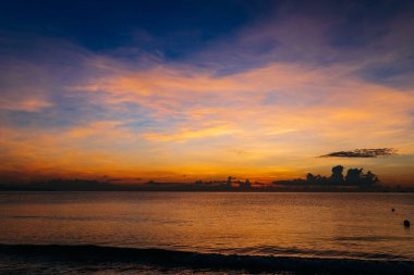 Güzel bir gün doğumu, bulutların arasından güneşin batışı, bulutların arasından güneş ışınları, küçük dalgalarla kumlu deniz kıyıları, denize yakın tropikal bir bölgede sıcak bir sabah ışığı..