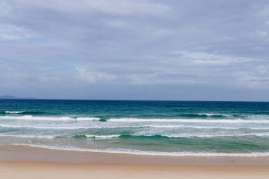 Yaz mevsimi deniz batımı mağara kumsalında, güneş, dalgalar ve bulutlar, güzel dramatik ışık, arkasında güneş.