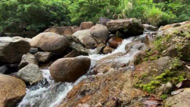 A mountain stream flows through large stones, foam from the flow of water. Clear transparent water. 