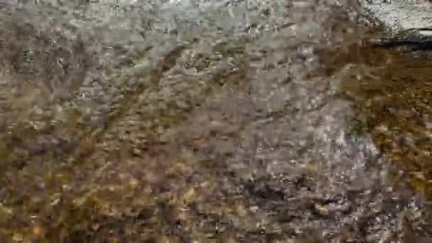Um córrego da montanha flui através das pedras grandes, espuma do fluxo da água — Vídeo de Stock