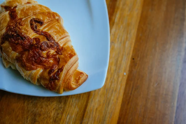 Chutný Čerstvý Croissant Bílém Talíři Sýrový Croissant Prázdném Dřevěném Hnědém — Stock fotografie