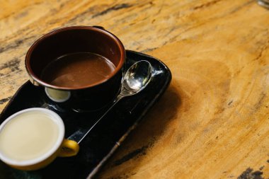 Bir fincan sıcak espresso koyu bir fincanda, siyah bir fincan üzerinde ve ayrı ayrı sütlü. Aromatik kahve eski bir ahşap kahverengi masanın üzerinde duruyor. Kopya yeri. Güne iyi bir başlangıç