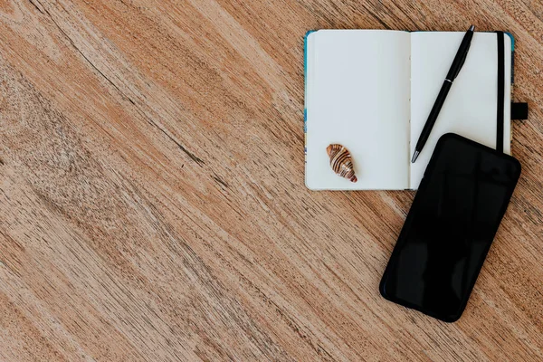 Düz yatış, beyaz kağıt ve kalem ile bir not defteri üst görünüm yaklaşan bir gezi planlamak için, ya da serbest plan. Güzergahı görmek için akıllı telefon. Not defterinde deniz kabukları ve yakınlardaki tropikal çarşaflar. Seyahat konsepti. Metin veya resim için yer, kopyalama yeri