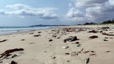 Kumlu deniz kıyısına atılan plastik çöpler, deniz sahilindeki çöpler. Ekolojik bir sorun. Çevre kirliliği
