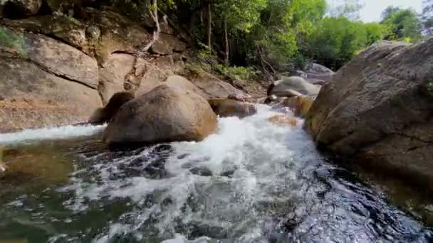 Ett stort vattenfall intill en flod. fjällbäck rinner genom stora stenar, skum från vattenflödet — Stockvideo