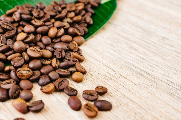 Yeşil yapraklı kahve çekirdekleri ve açık ahşap bir masaya yayılmış taze americano, espresso, doğal arka plan, üst manzara, yakın çekim tanecikleri, düz yatak, metin eklemek için yer, kopyalamak için yer