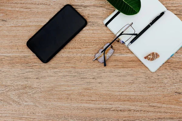 Düz yatış, beyaz kağıt ve kalem ile bir not defteri üst görünüm yaklaşan bir gezi planlamak için, ya da serbest plan. Güzergahı görmek için akıllı telefon. Not defterinde deniz kabukları ve yakınlardaki tropikal çarşaflar. Seyahat konsepti. Metin veya resim için yer, kopyalama yeri