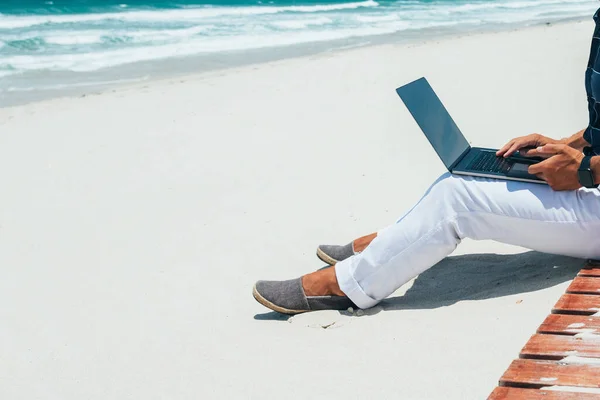 ノートパソコンを使って砂浜の海岸に座ってる男 移動中の遠隔作業に取り組んでいます ブロガー フリーランスはコンテンツ作業計画を立てる — ストック写真