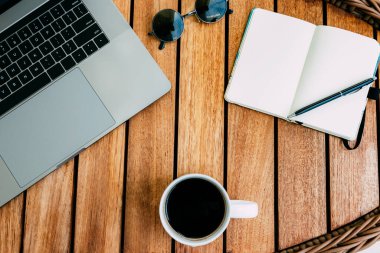 Çalışma alanı, dizüstü bilgisayar, bir fincan kahve ve kayıt için not defteri olan kahverengi ahşap bir masa. Serbest meslek kavramı. Uzaktan kumanda. Yer kopyala