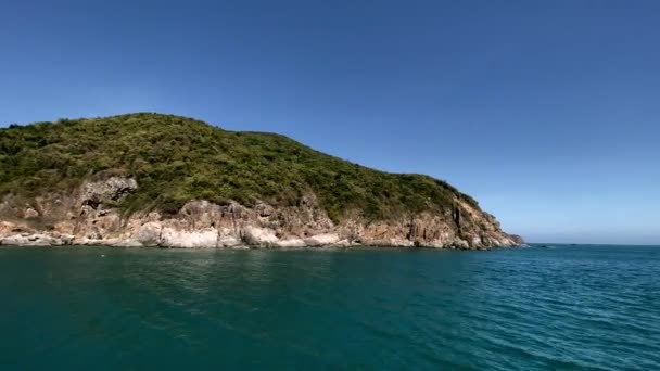 Vue de la côte rocheuse de l'île depuis le navire. Bleu calme de la mer, ciel bleu clair avec une montagne en arrière-plan 