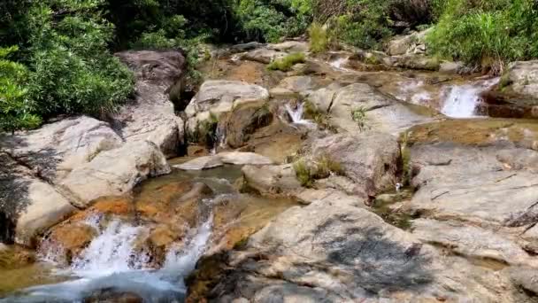 Горный поток протекает через большие камни, пену из потока воды. Водопад у реки — стоковое видео