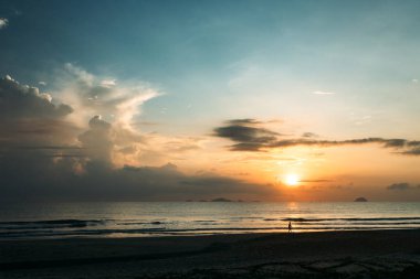 Güzel bir gün doğumu, bulutların arasından güneşin batışı, bulutların arasından güneş ışınları, küçük dalgalarla kumlu deniz kıyıları, denize yakın tropikal bir bölgede sıcak bir sabah ışığı..