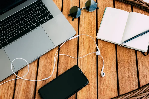 Flat lay of the workspace with a laptop, on a brown wooden table with a smartphone a cup of coffee and a notebook for recording cases. business concept. Remote work. Copy space, wood background