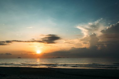 Güzel bir gün doğumu, bulutların arasından güneşin batışı, bulutların arasından güneş ışınları, küçük dalgalarla kumlu deniz kıyıları, denize yakın tropikal bir bölgede sıcak bir sabah ışığı..