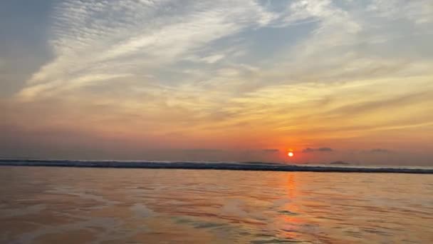 熱帯のビーチの上に太陽の夜明け。明るい太陽がちょうど海の上に上昇し、波と空のオレンジ色です。穏やかな波 — ストック動画