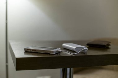 Otel odasındaki yatak odasının içinde elektrik bankası olan cep telefonu ya da akıllı telefon, sıcak renklerde otel..