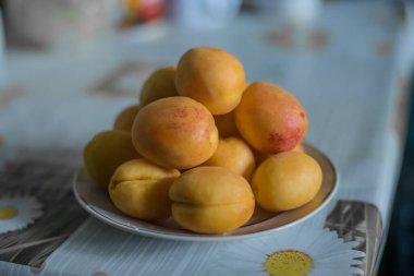 Güzel ve ağız sulandıran şeftaliler ya da kayısılar, beyaz bir tabakta servis ve mutfakta yatıyorlar..