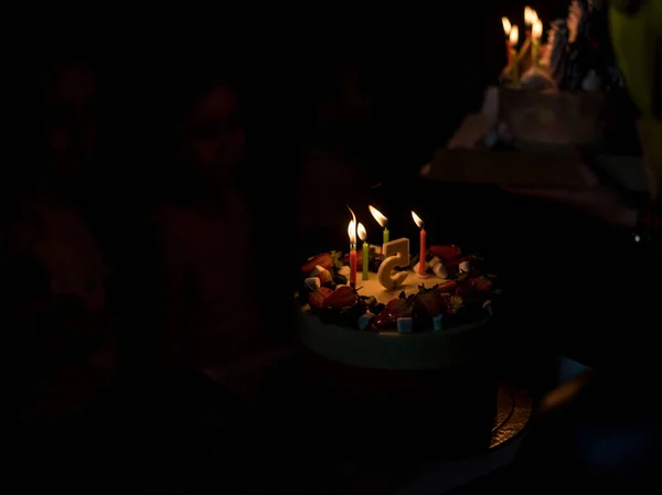 Beautiful view of the cake with candles and congratulations to the girls happy birthday and five-year anniversary on a dark background.