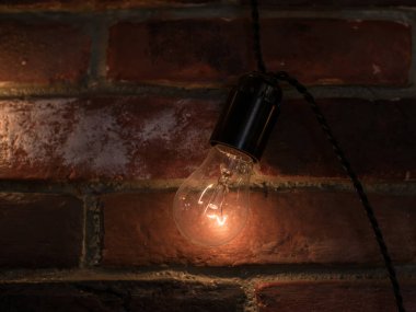 Parlayan parlak parlak ışık ampullerinden oluşan bir çelenk ile dokuma tuğla duvar. Sıcak renkli ve açık renkli..