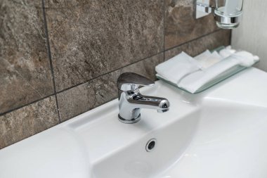 Moda ve pahalı bir banyo ve tuvaletin içi kahverengi dekoratif taş ve fayanslardan yapılmıştır, beyaz seramik ve solgunluk elementleriyle..