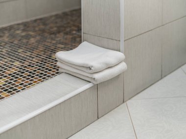 Beyaz Terry ve keten yumuşacık havlular kahverengi dekoratif taştan yapılmış şık ve pahalı bir banyo ve tuvaletin içinde.