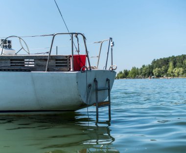 Güzel beyaz bir yat, tekne, küçük bir gemi, denizde yelkenleri olan bir gemi, okyanus, ama kıyı açıklarında sakin..