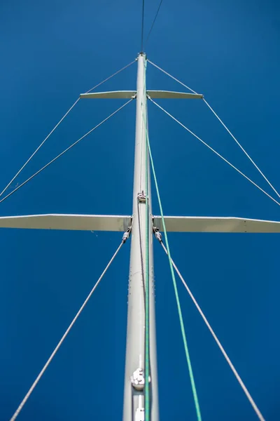 Beautiful view of the mast of the yacht, rigging, rigging against the blue sky on a sunny summer day.