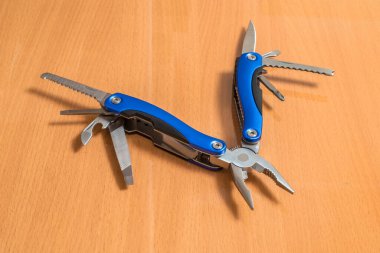 Güzel bir katlama bıçağı, seyyar bir erkek aleti ve ahşap bir yüzey ve arka planda çalışmak ve onarmak için çeşitli araçları olan bir aksesuar..