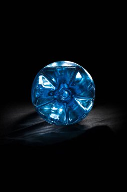 Temiz içme suyu için büyük bir plastik şişenin ucunda ve altında güzel mavi bir çizgi ya da siyah arka planda ferahlatıcı bir içecek..