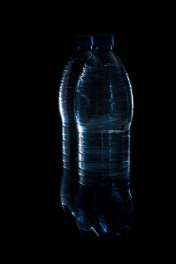 Temiz içme suyu için iki büyük plastik şişenin güzel mavi ana hatları ya da siyah arka planda ferahlatıcı bir içecek..