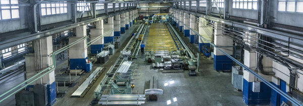Industrial landscape at the plant, a huge workshop with machines, rolling and stretching mills for the manufacture of aluminum metal and blanks in the form of long profiles.