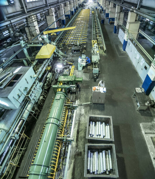 Industrial landscape at the plant, a huge workshop with machines, rolling and stretching mills for the manufacture of aluminum metal and blanks in the form of long profiles.