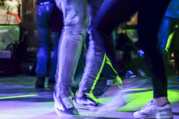 stock image Beautiful view and scene on the feet, shoes of dancing people, youth in a club or bar on a dark background with illumination.