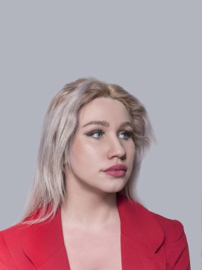 Güzel genç kız, sarışın, iş kadını kırmızı ceketli ve gri arka planda..