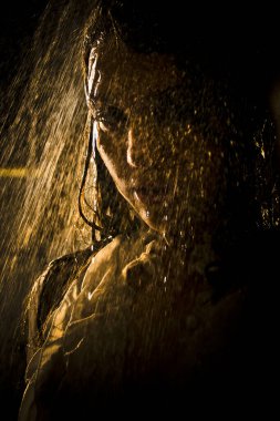 Kavramsal bakış açısı ve genç, şehvetli, güzel bir kızın sahnesi. Karanlık bir arka planda, bir su stüdyosunun arka planında, güçlü bir su püskürtüsünün altında yıkanan bir kadın..