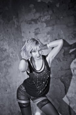 Modern ve genç, baştan çıkarıcı, duygusal, güzel bir sarışının kavramsal portresi. Koyu bir bluz, yırtık tayt ve çorap giymiş bir kadın. Yıkık bir binanın, duvarların, tuğlaların içinde.