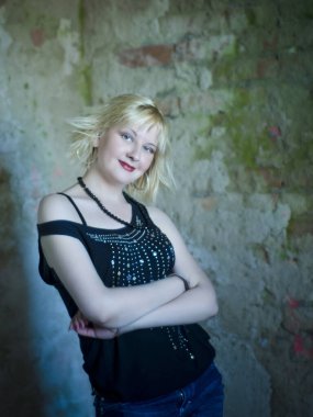 Modern ve genç, baştan çıkarıcı, duygusal, güzel bir sarışının kavramsal portresi. Koyu bir bluz içinde, yıkılmış bir binanın içinde, duvarların, tuğlaların içinde.