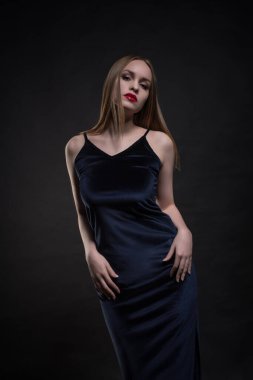 Şık, genç, baştan çıkarıcı, duygusal, güzel bir kızın portresi, sarı düz saçlı bir kadın, dudaklarında kırmızı ruj, siyah ve koyu bir arka planda siyah bir elbise..