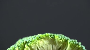 Brokoli yeşil saplı siyah zemin üzerinde dilimlenmiş makro. Dikey panorama, 4k